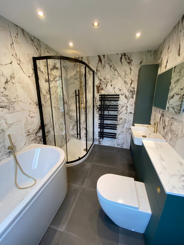 Modern bathroom with marble-patterned walls, curved black-framed shower enclosure, freestanding bathtub, toilet, and vanity sink